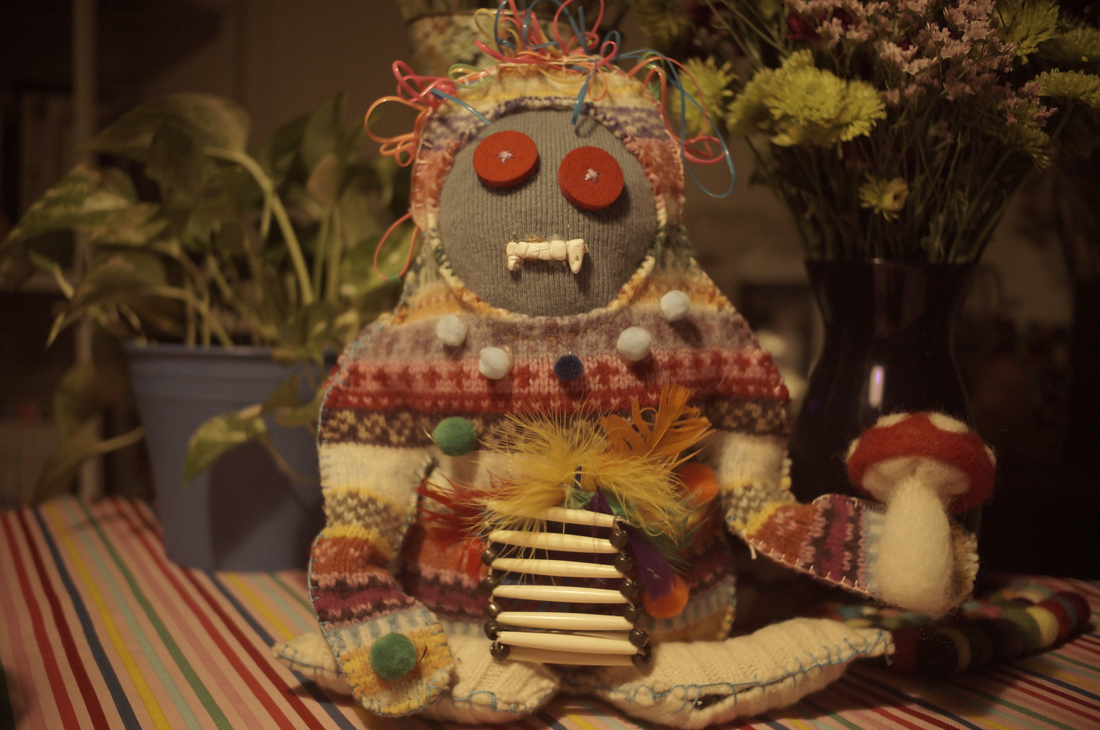 A stuffed doll made of mixed materials, primarily cut sweater. 