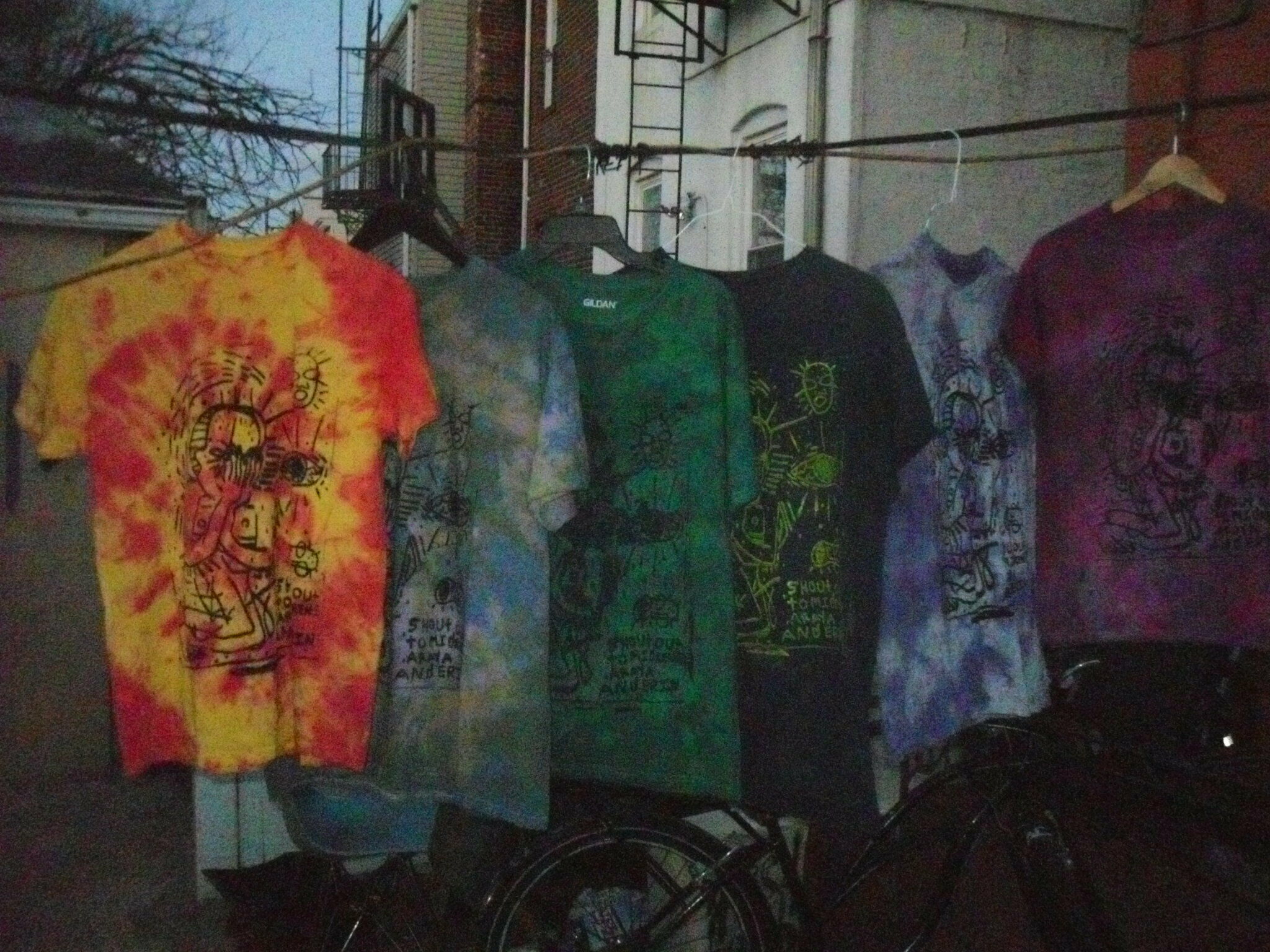 A series of tie-dye shirts hanging on a clothesline. 