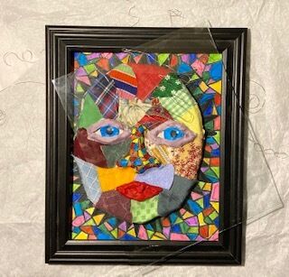 A framed mosaic piece with a face in the center. 