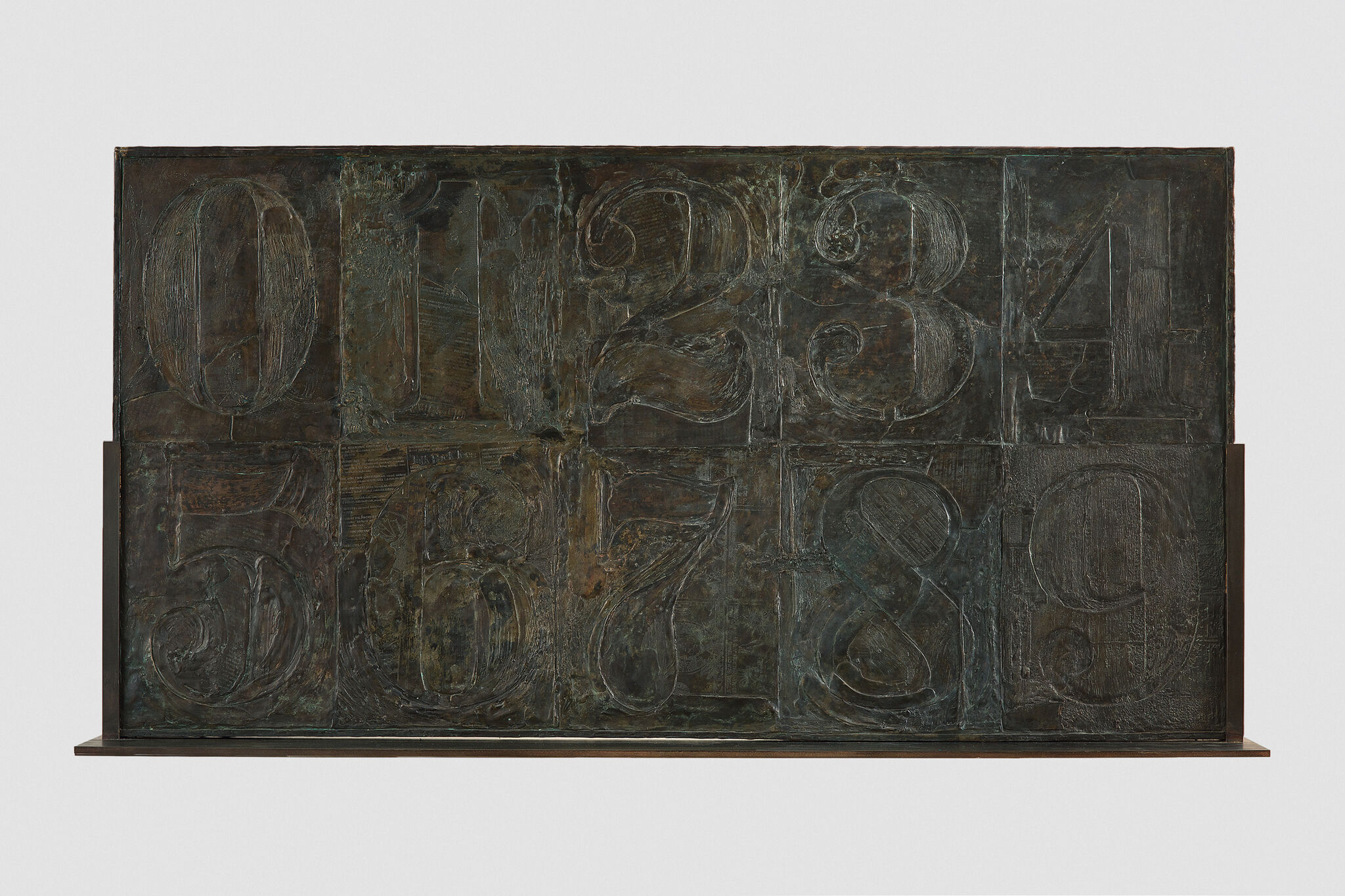 Series of numbers, 0 through 9, arranged in two rows on top of each other in a wide rectangle, and subtly distinguished from each other and their bronze background by differing textural patterns.