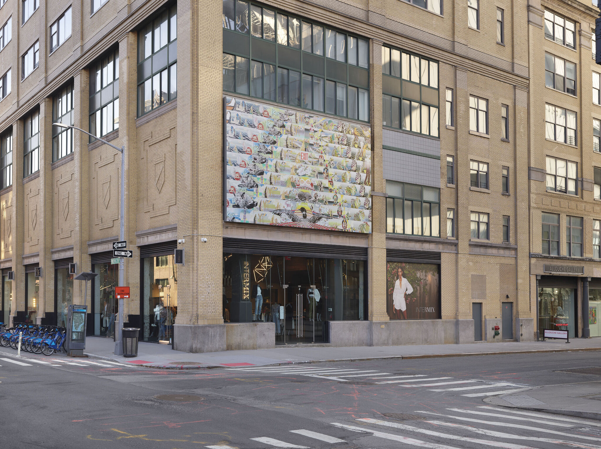 A large billboard comprised of Andrea Carlson's piece Red Exit is installed on the side of a building above two glass doors.