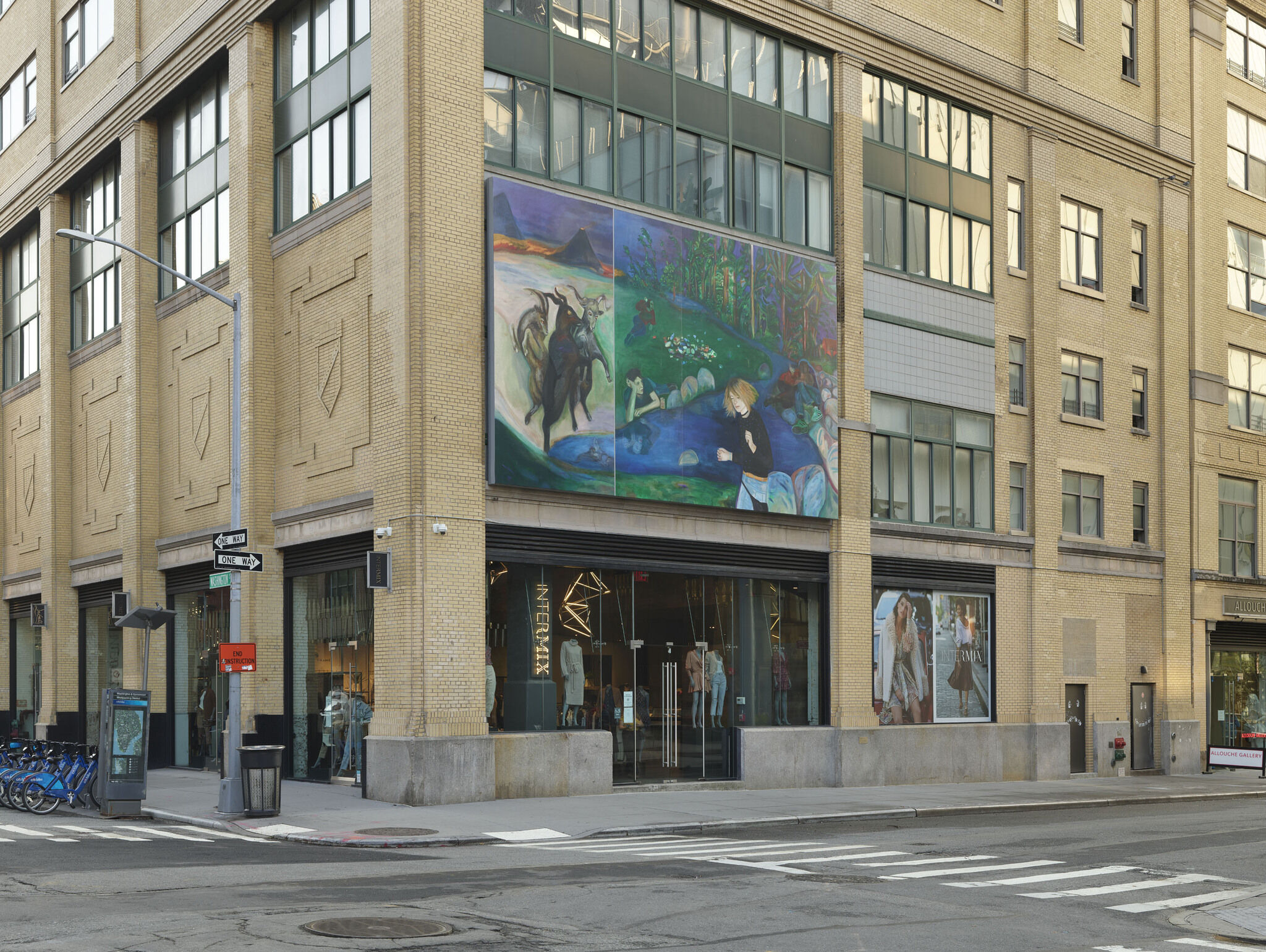 A large billboard comprised of Jill Mulleady's piece, We Wither Time into a Coil of Fright, is installed on the side of a building above two glass doors. 
