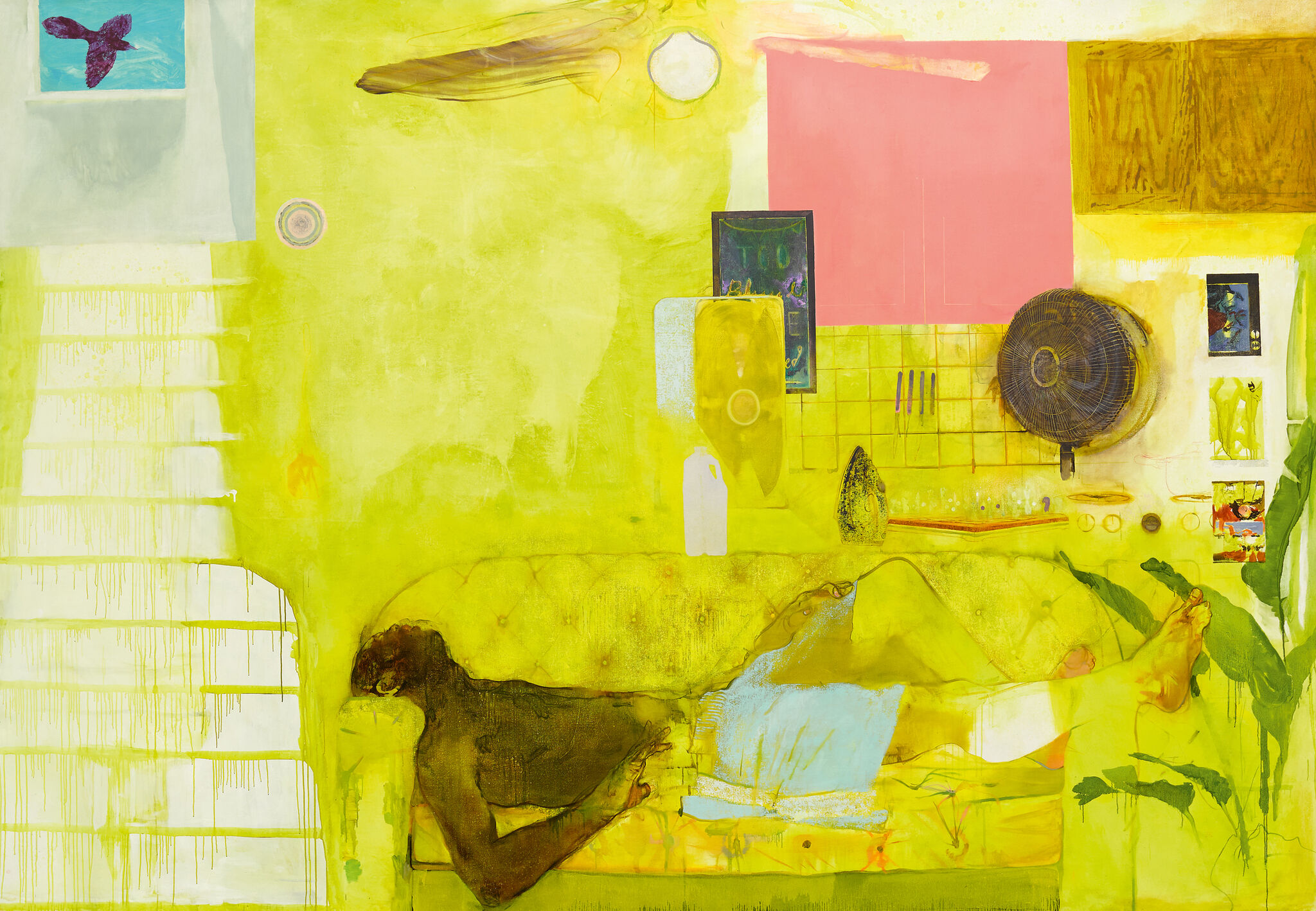 A man lies on a couch in a room whose predominant color scheme is yellow, with a bare wall and assorted furnishings in the background.