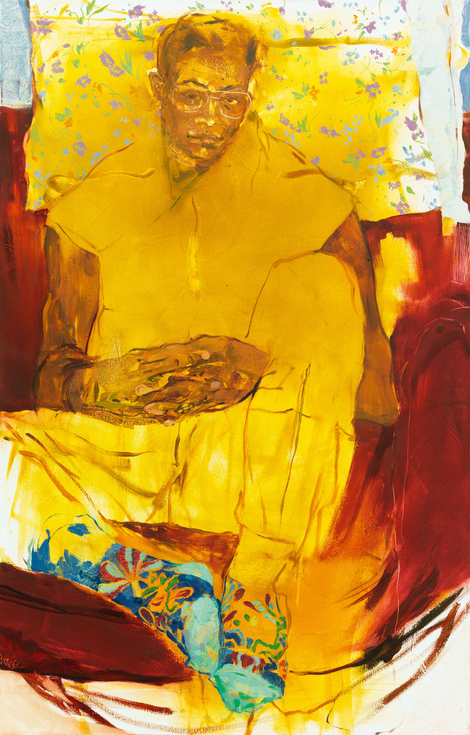 A figure in glasses sits, nearly cross-legged, in a relaxed posture with interlaced fingers.