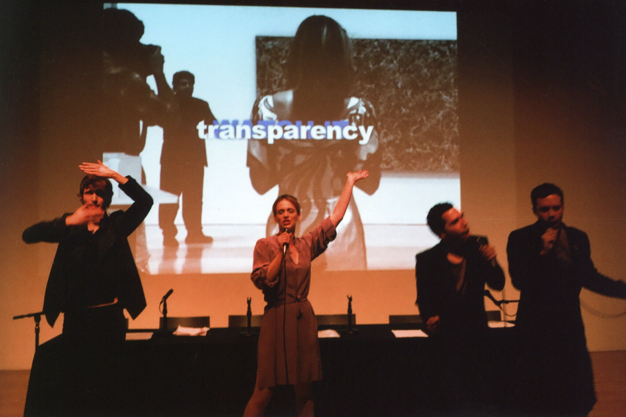 Four people performing in front of a projected screen.