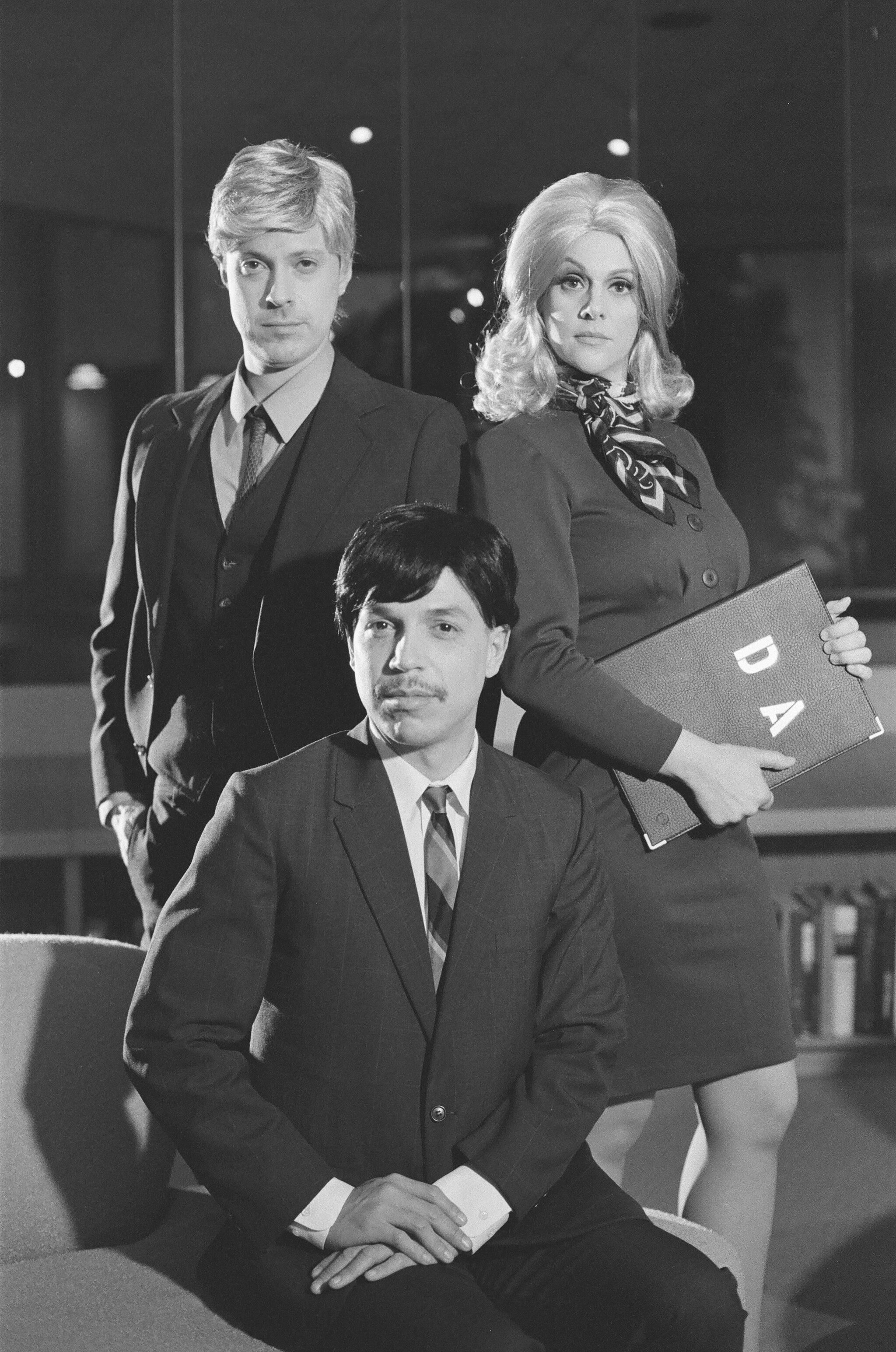 A black and white portrait of three people facing the camera. 