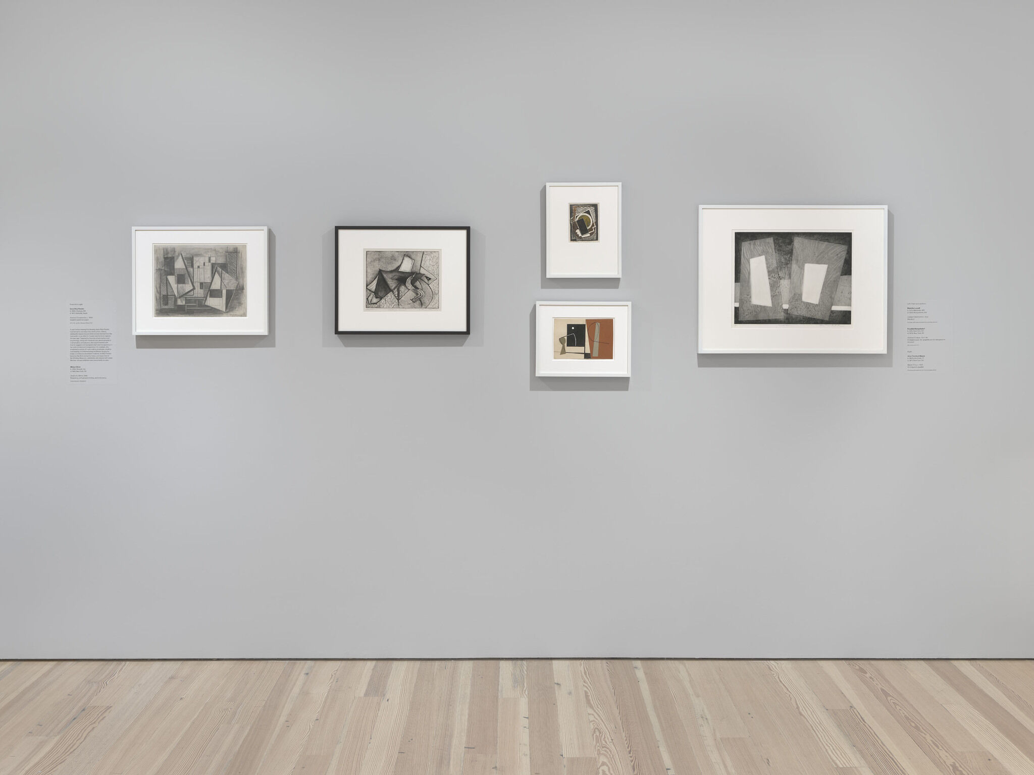 Five framed pieces are mounted on a white exhibition wall. 