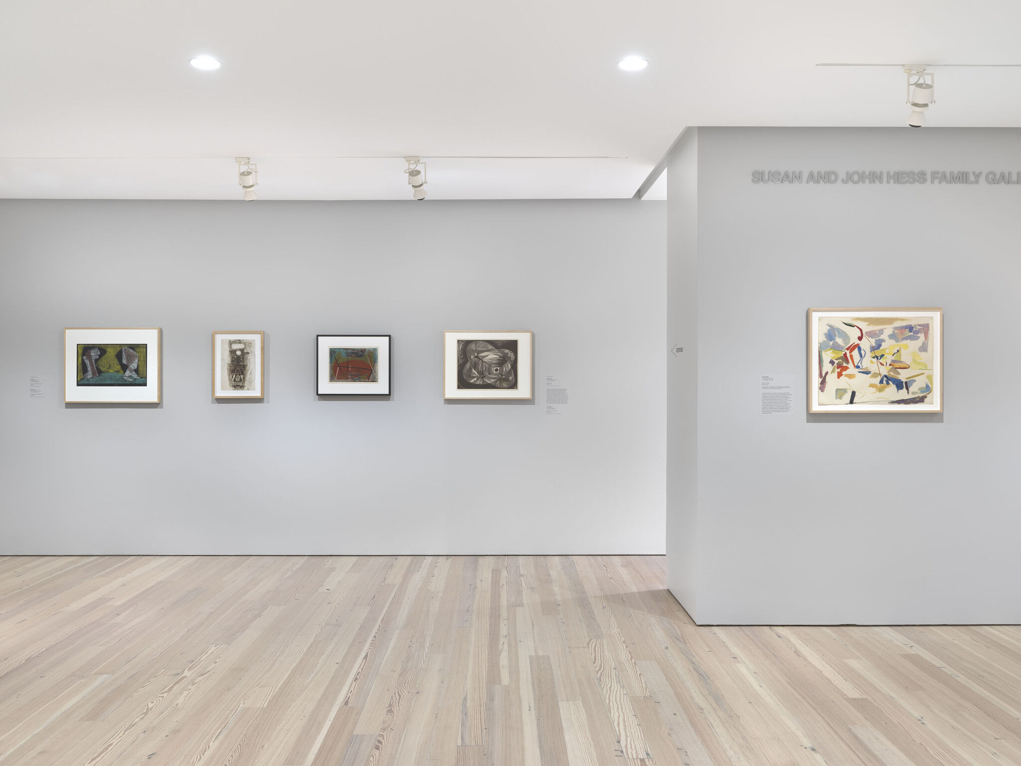 Five framed pieces mounted across two neighboring exhibition walls.