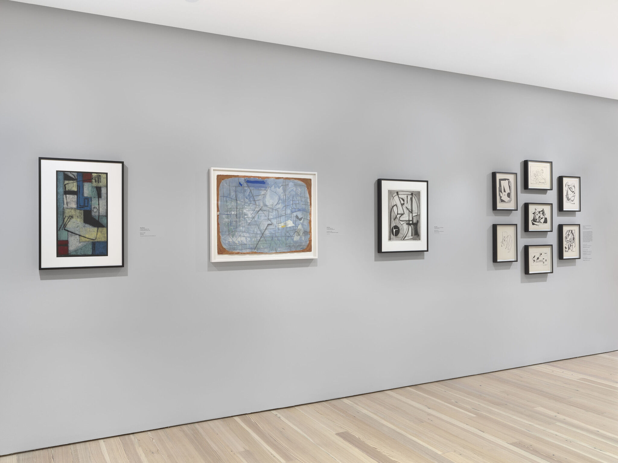 Ten framed pieces are mounted on a white exhibition wall.
