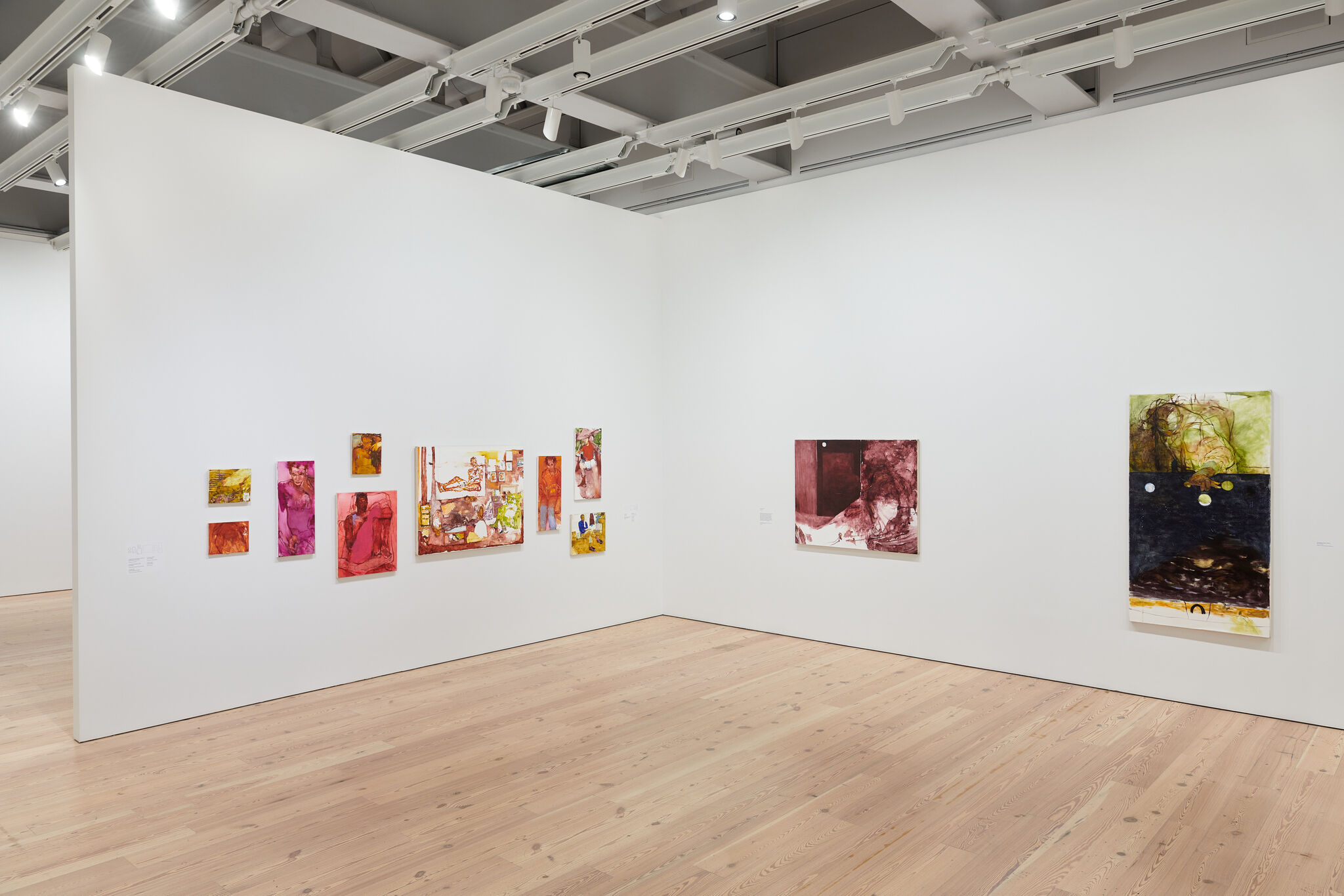 A white exhibition wall with eleven works mounted next to each other. 