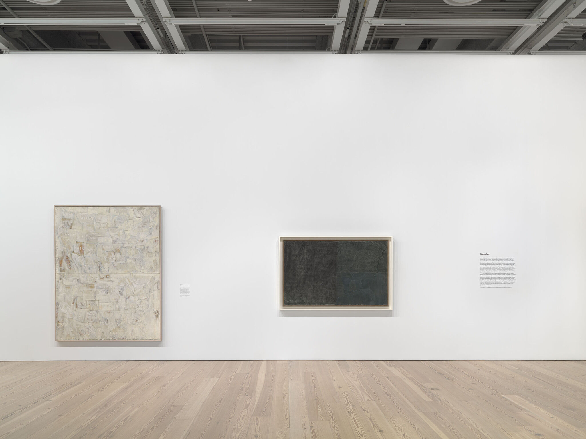 A white exhibition wall with two works mounted next to each other. 