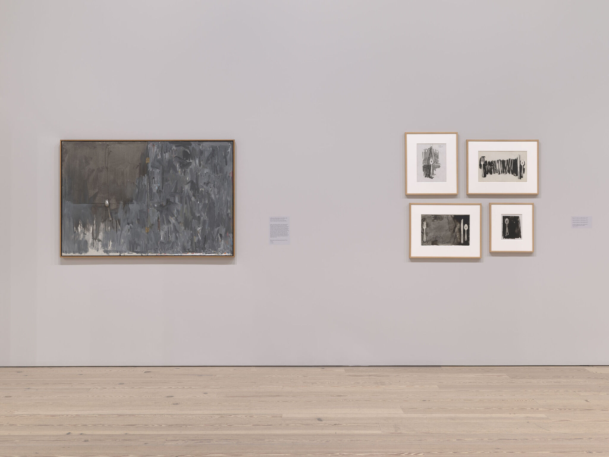 A white exhibition wall with five framed works mounted next to each other.