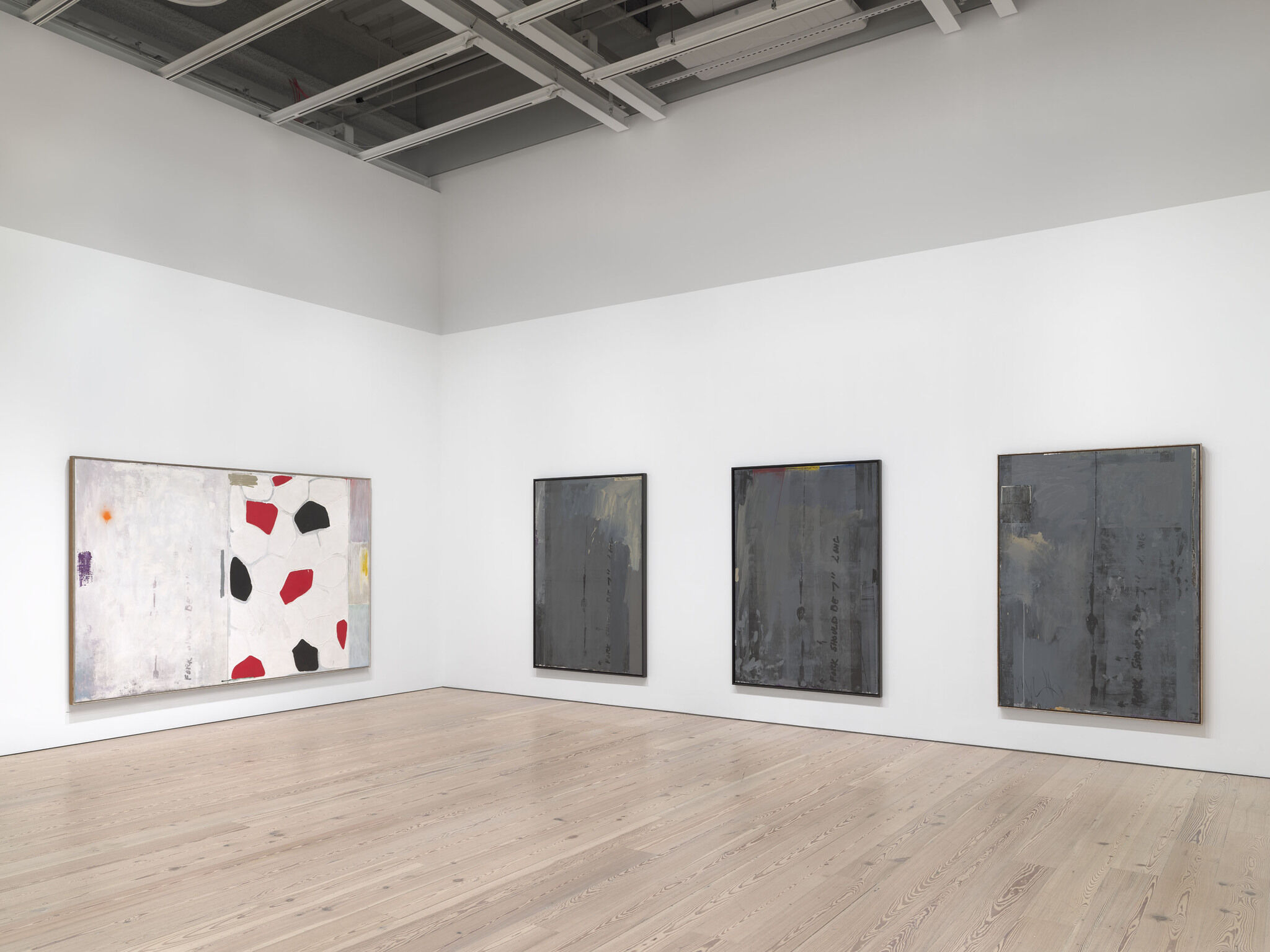 A white exhibition wall with four works mounted next to each other. 