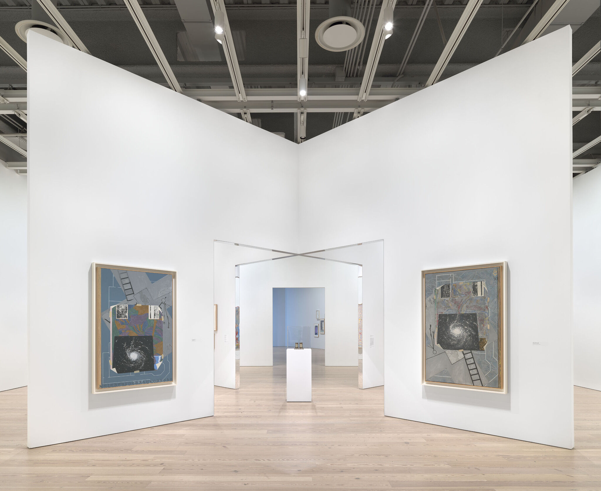A white exhibition room with six works mounted across separate walls. 