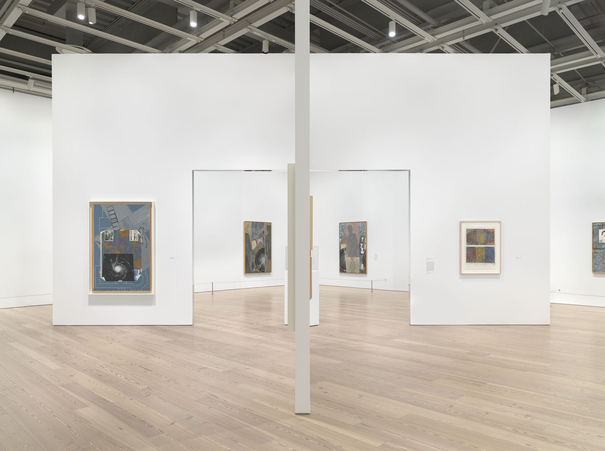 A white exhibition room with four works mounted across two separate walls. 