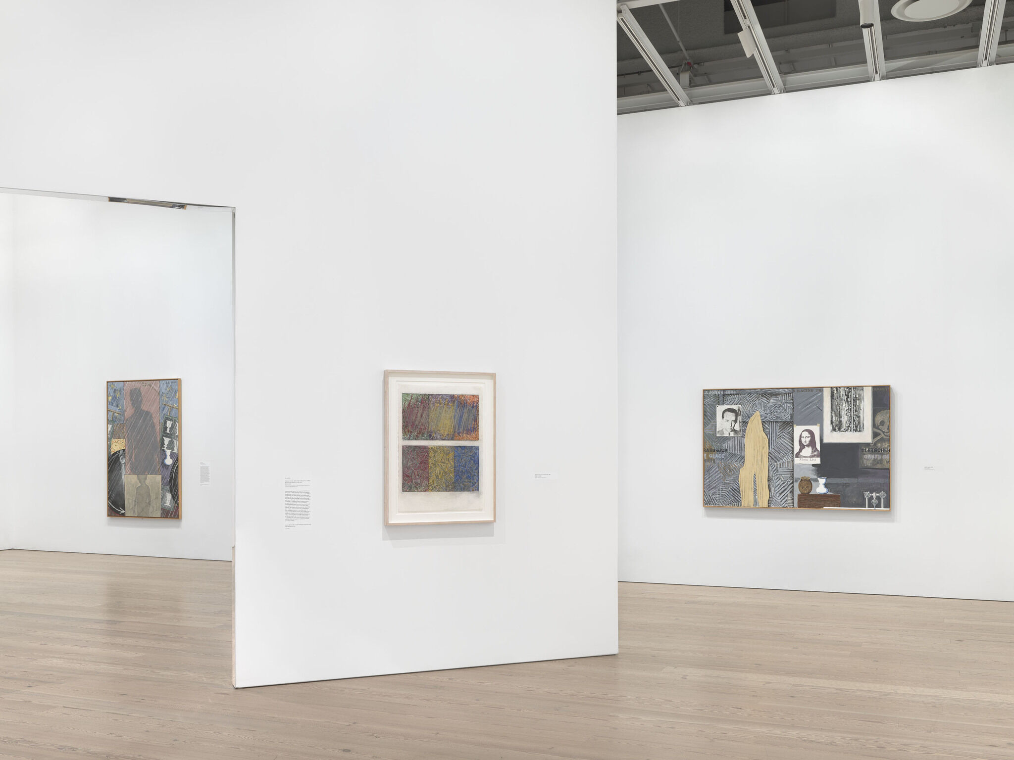 A white exhibition room with three framed works mounted across two separate walls. 