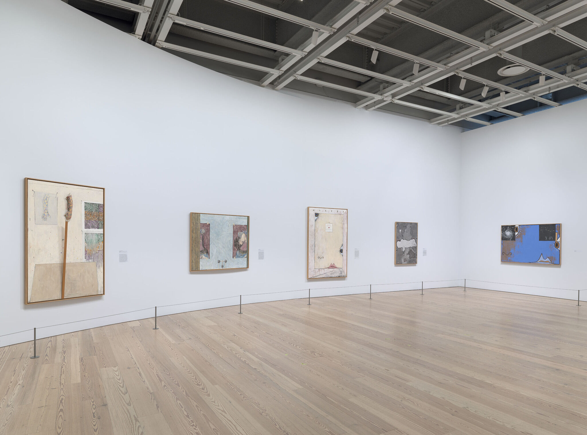 A white exhibition wall with five works mounted next to each other. 