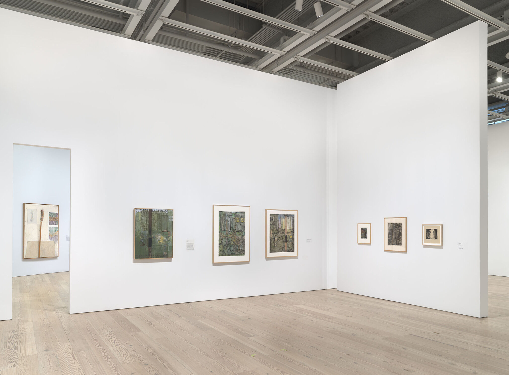 A white exhibition room with seven works mounted across three separate walls. 
