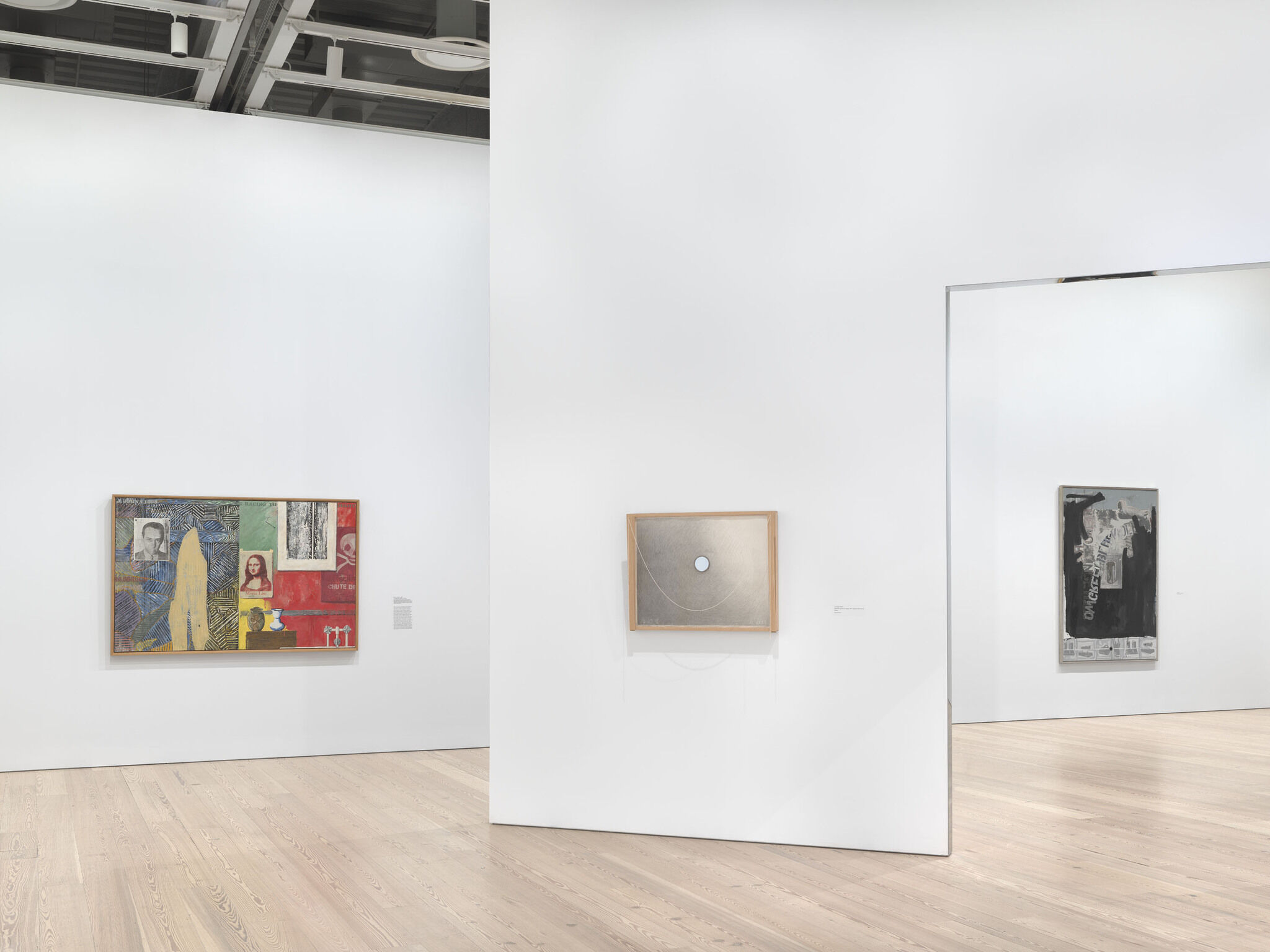 A white exhibition room with three works mounted across two separate walls. 