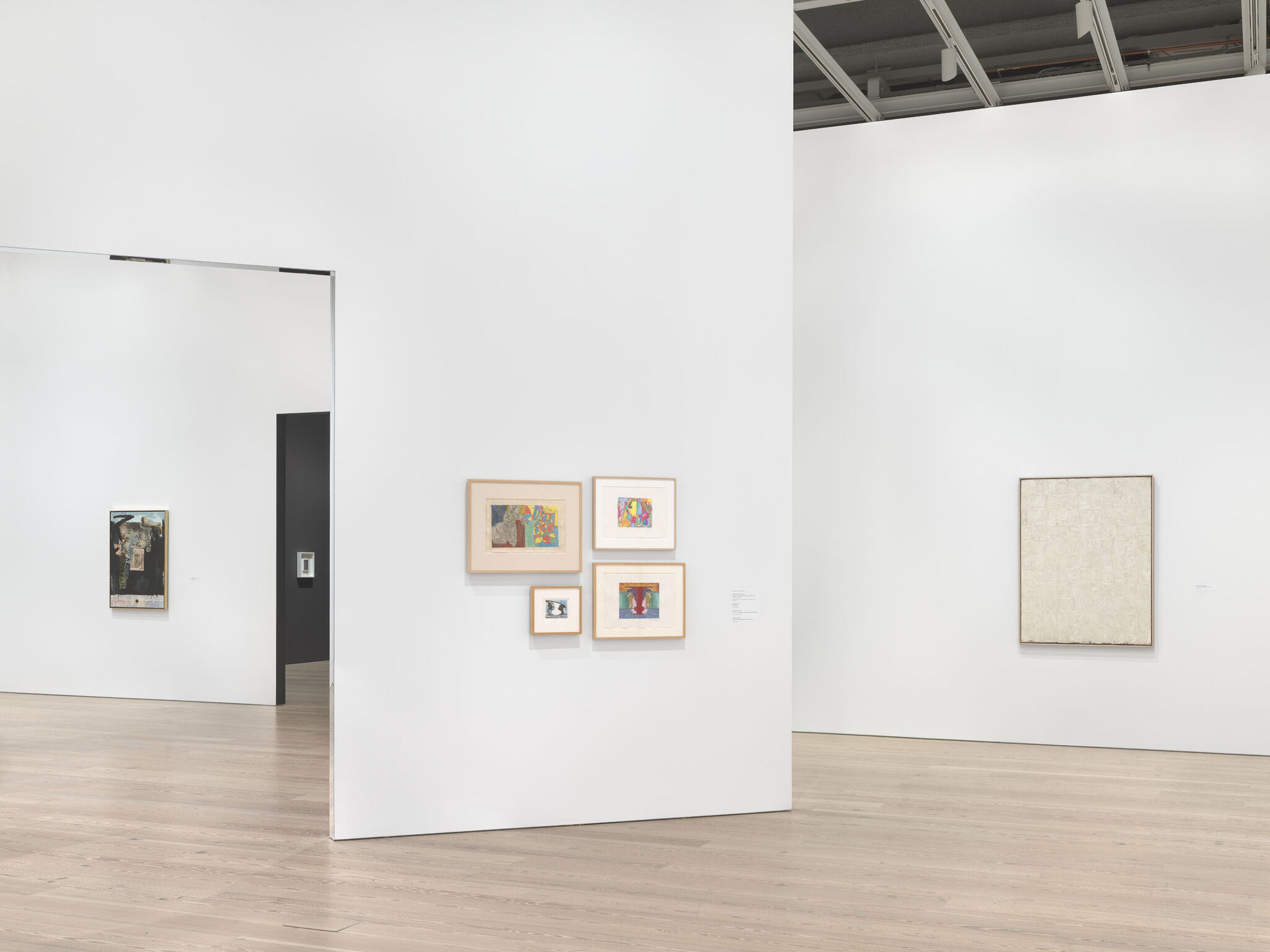 A white exhibition room with six works mounted across separate walls. 