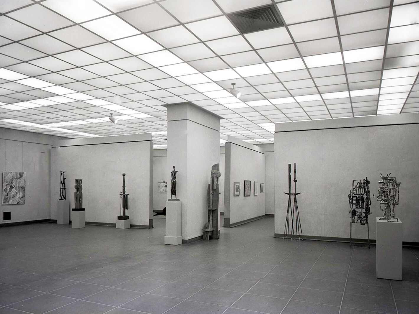 Black-and-white photograph of a gallery of sculptures.