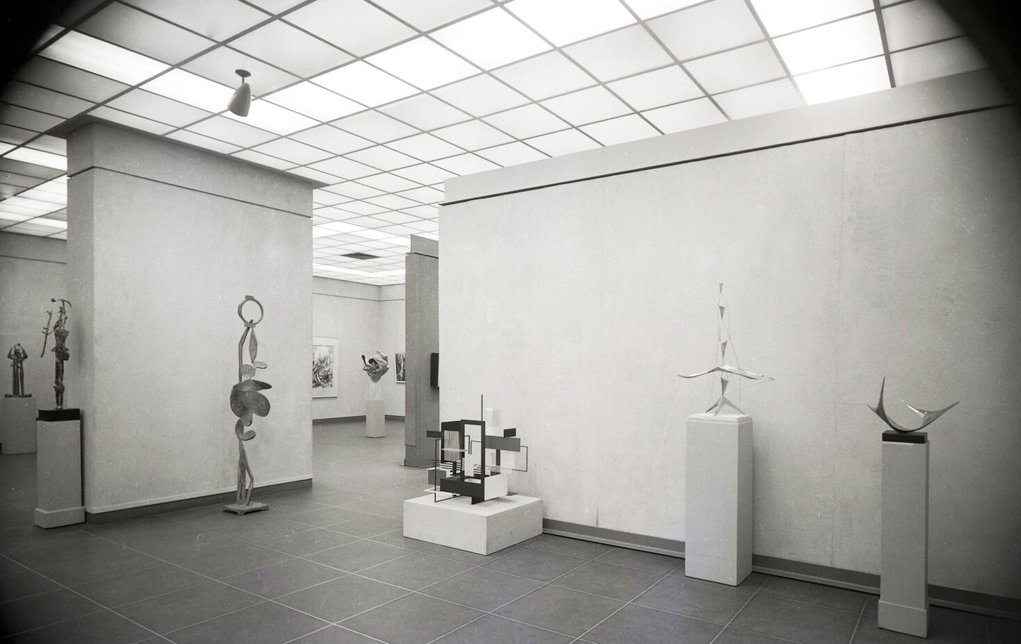 Black-and-white photograph of a gallery of sculptures.