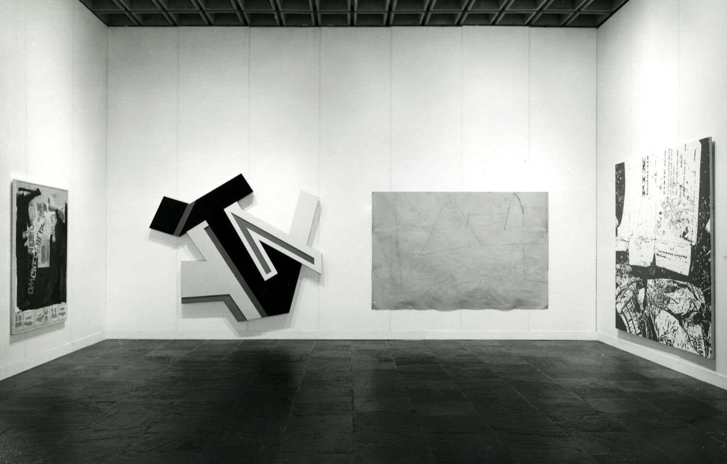 Black-and-white photograph of works of art hanging in a gallery.
