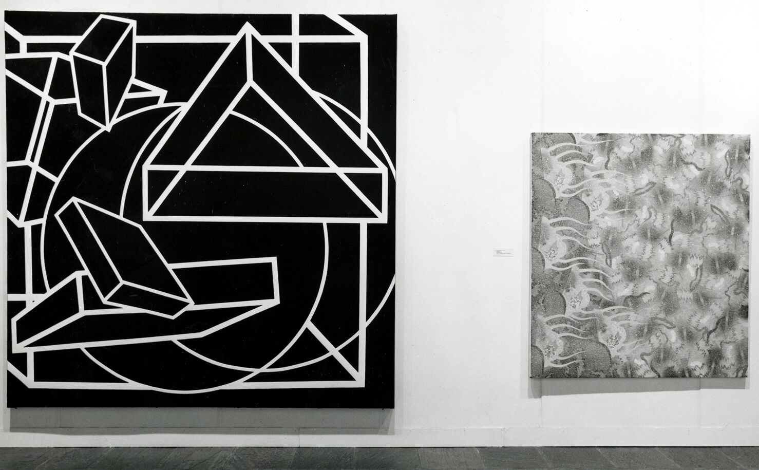 Black-and-white photograph of two paintings hanging on a wall