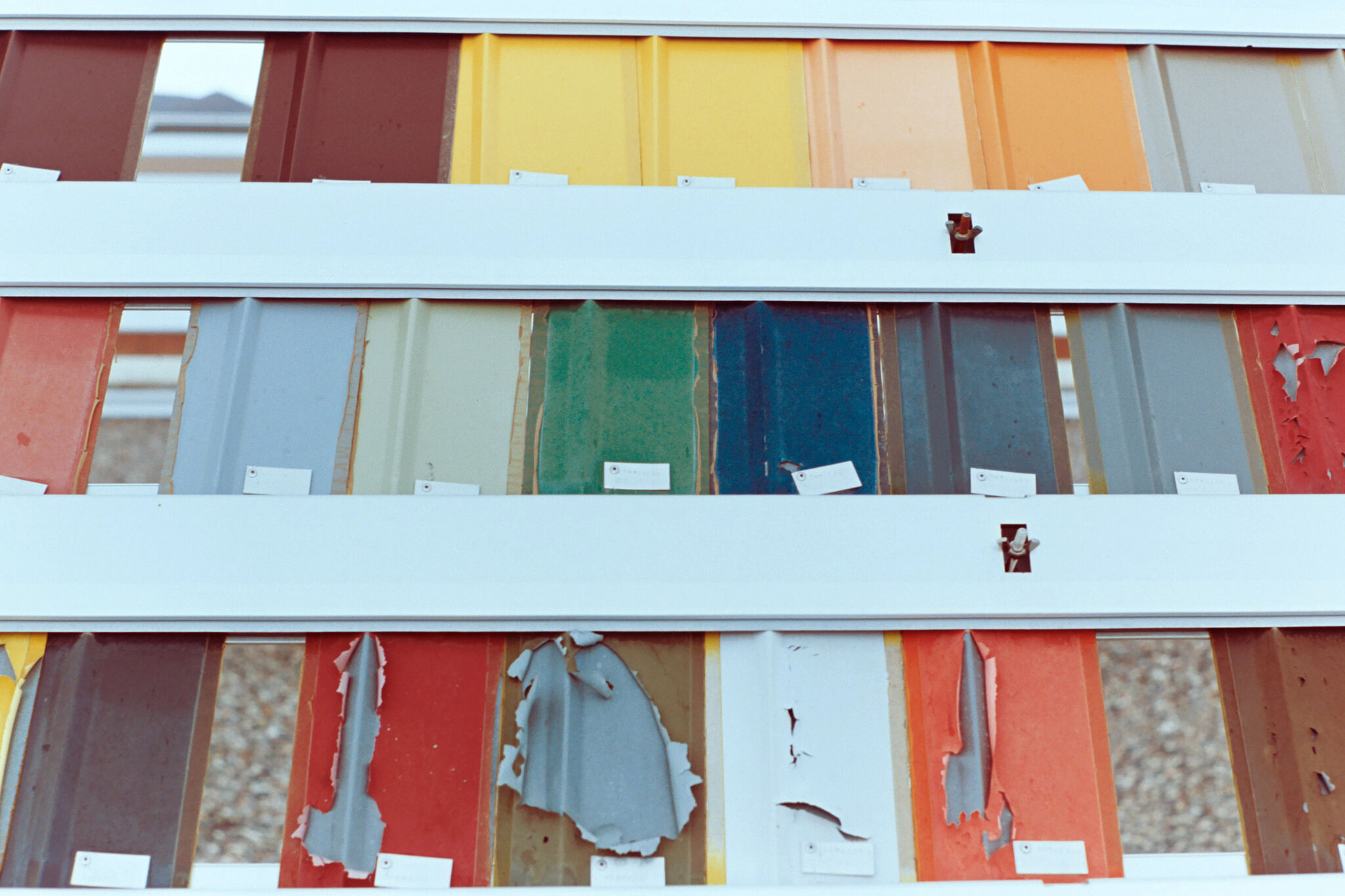 Panels of colorful, painted metal siding, some of which are damaged and peeling.