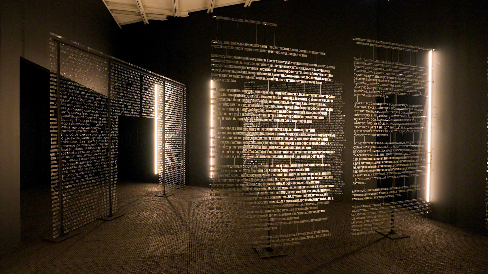 Many large transparent panels with metal, glowing text on top of them, as if floating in air