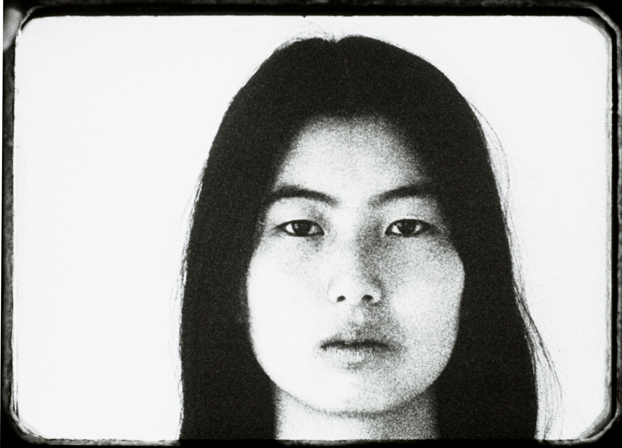 Black-and-white image of a female face, staring directly at the camera with her lips slightly parted.