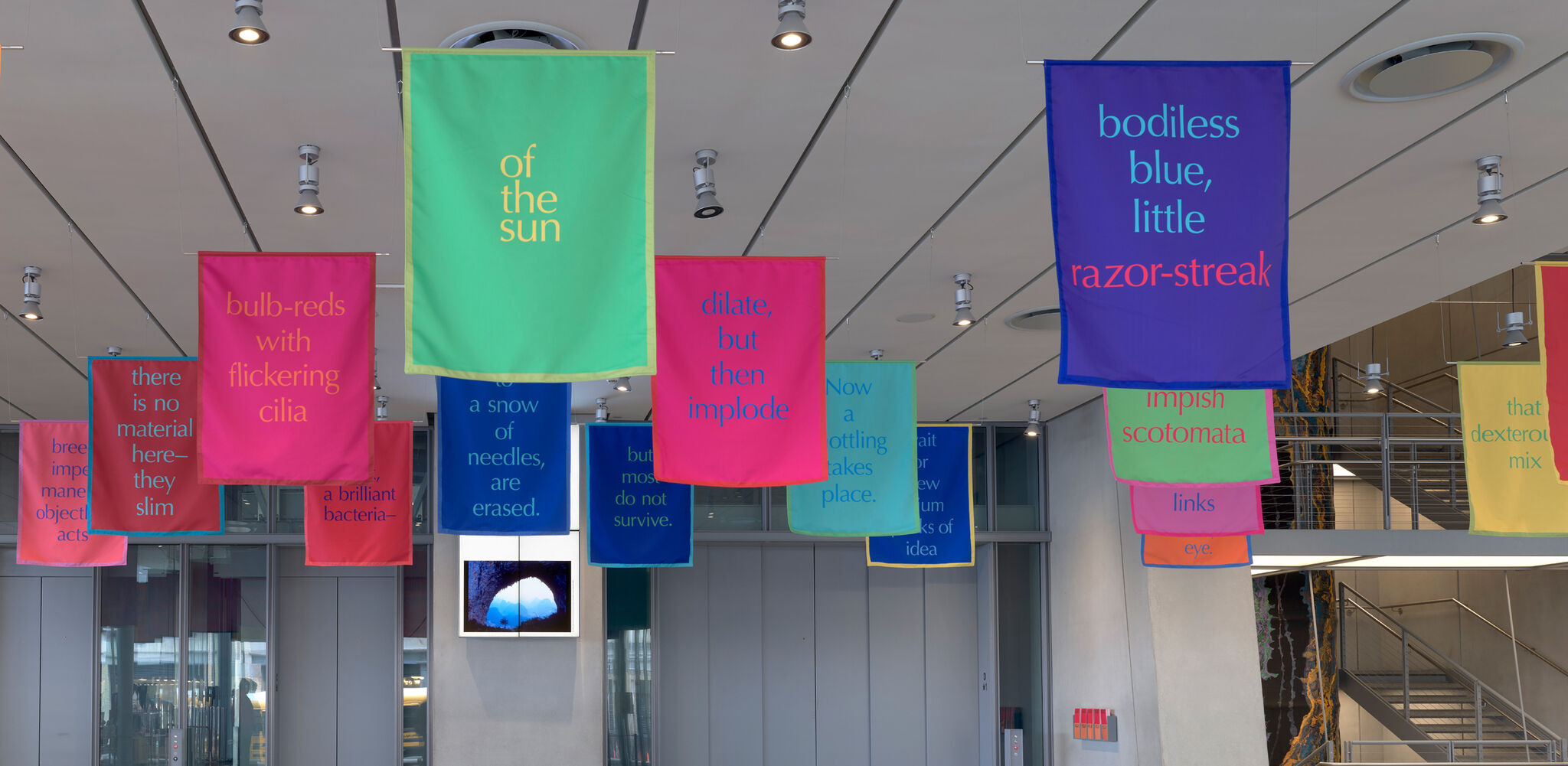 Colorful banners with lines of text on them, suspended from a ceiling.