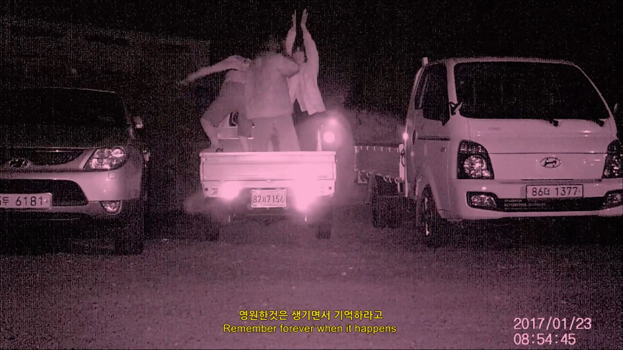 Pink-tinted image of three parked cars, with three people dancing in the back of a pickup truck. The time stamp in the bottom right corner reads "2017/01/23 08:54:45".