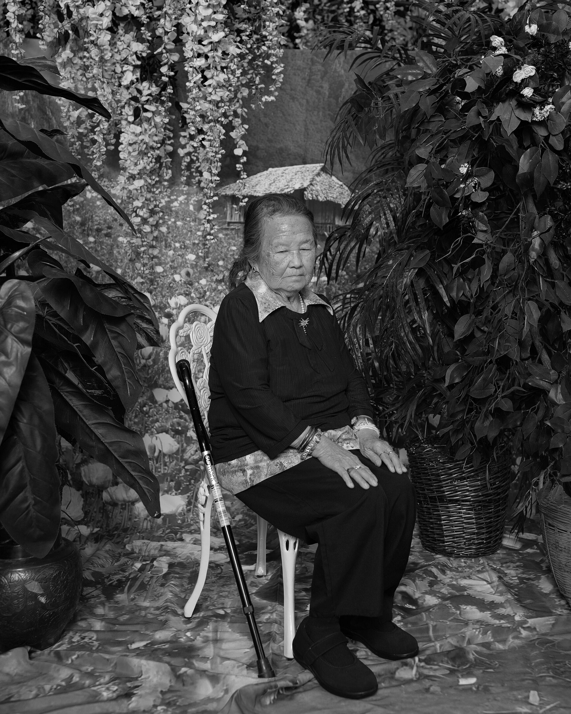 A sitting woman surrounded by plants.