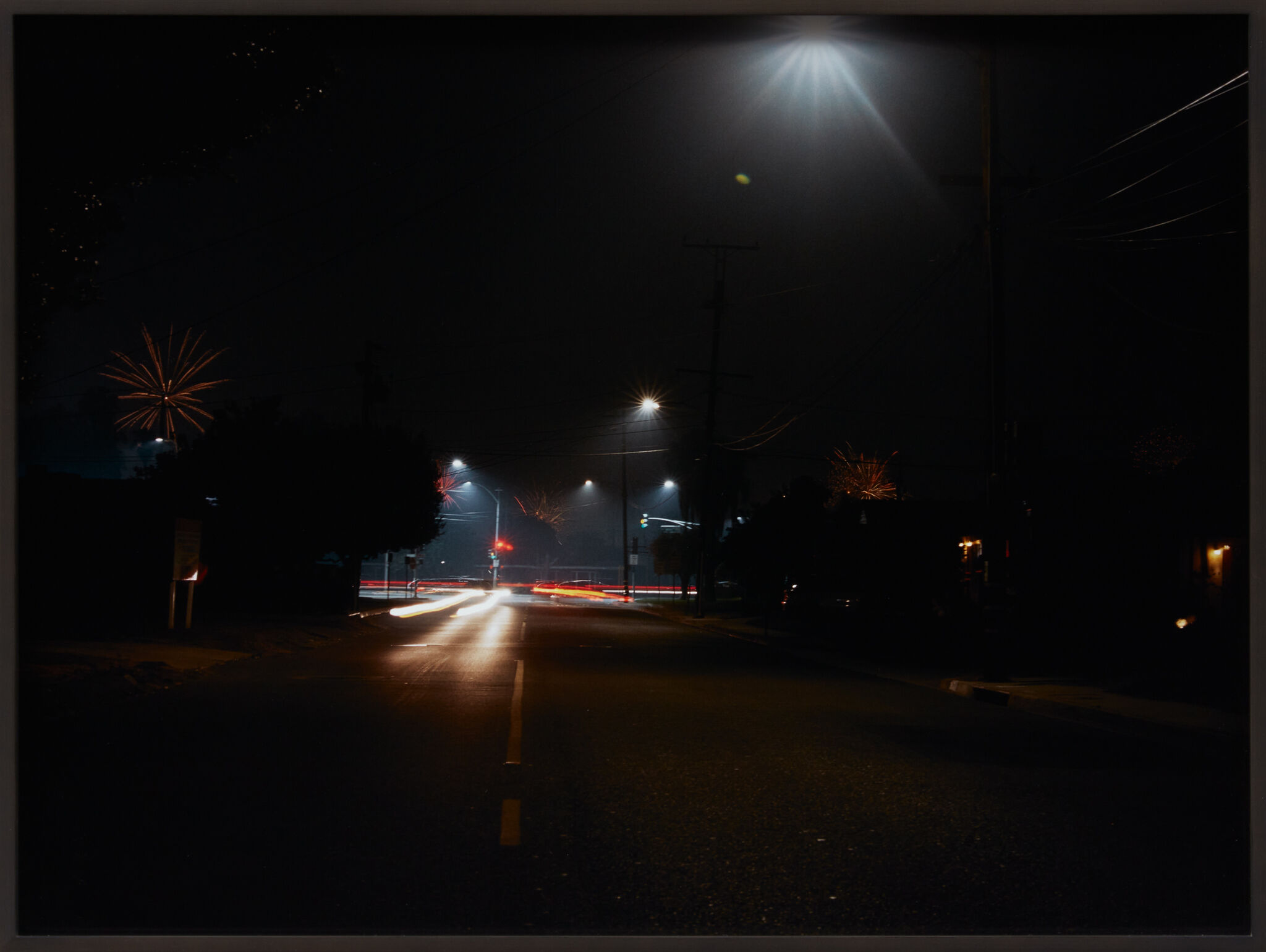 A dark street with shining radial, firework-like lights.