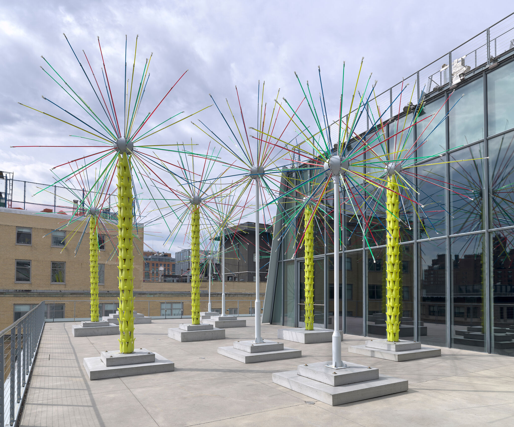 An outdoor installation of several tree-like objects with radiating straight thin sticks on top of of each.