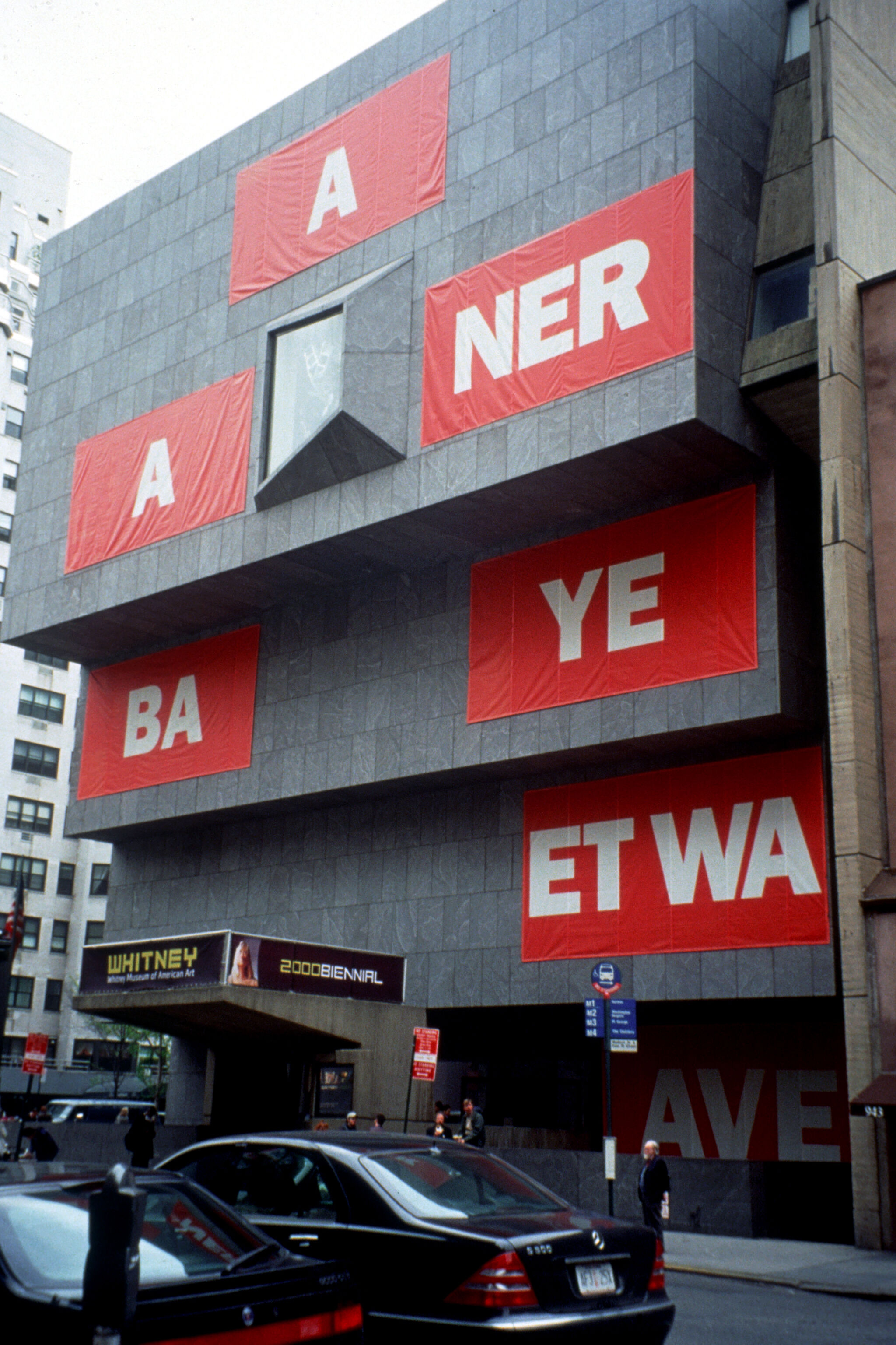 Red banners on the exterior of a tiered concrete building facade.