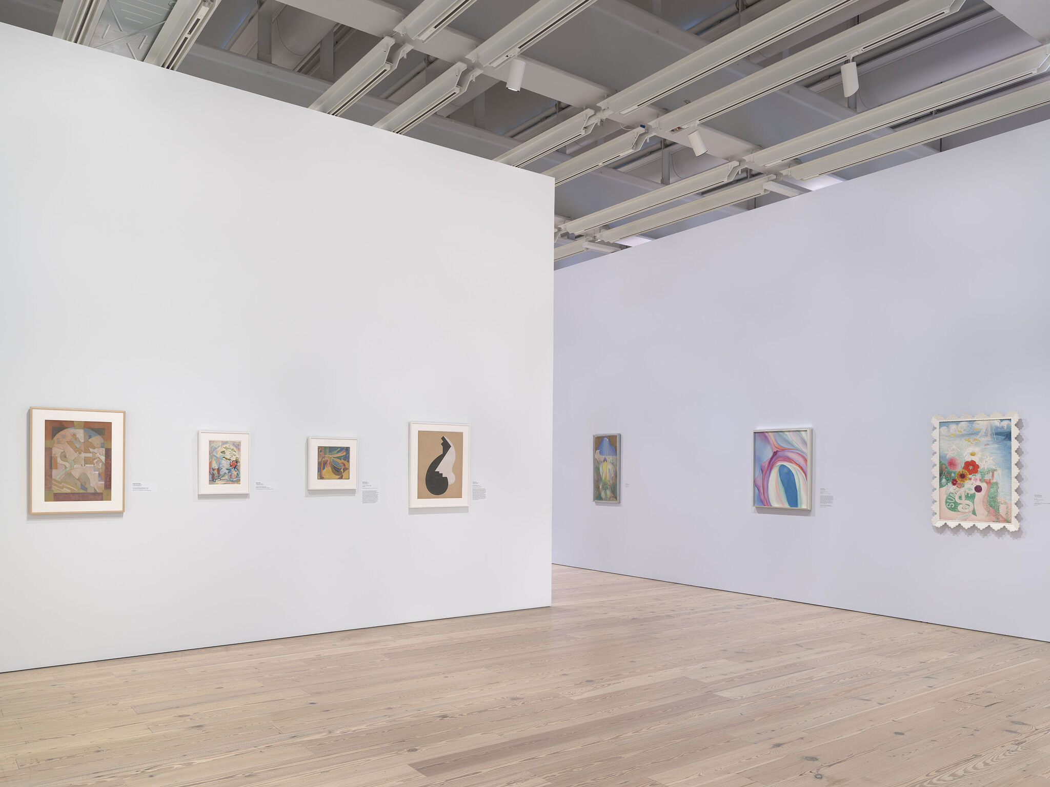 A white exhibition room with seven works mounted across two walls. 