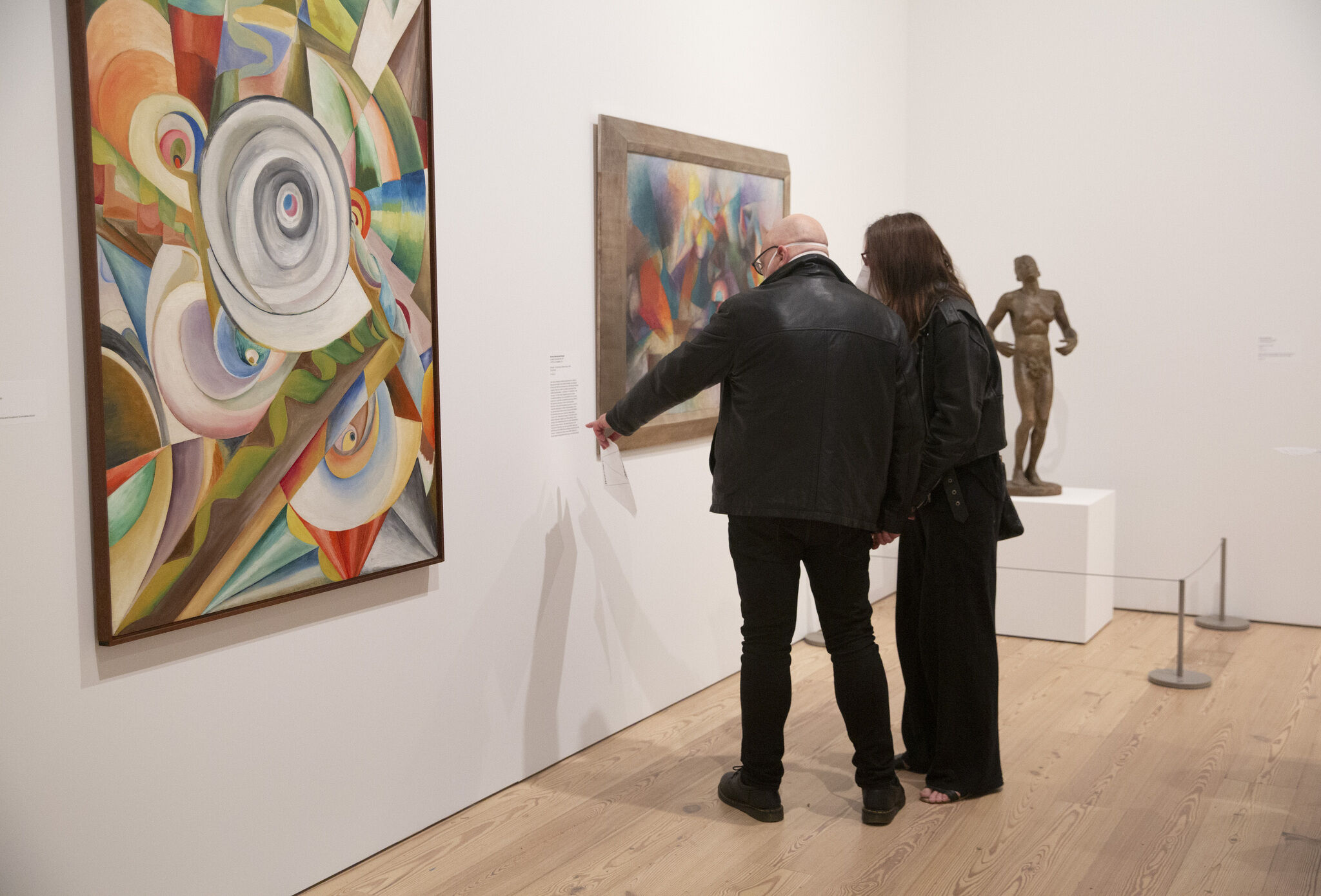 Two people in the Whitney's galleries point and look at abstract paintings.