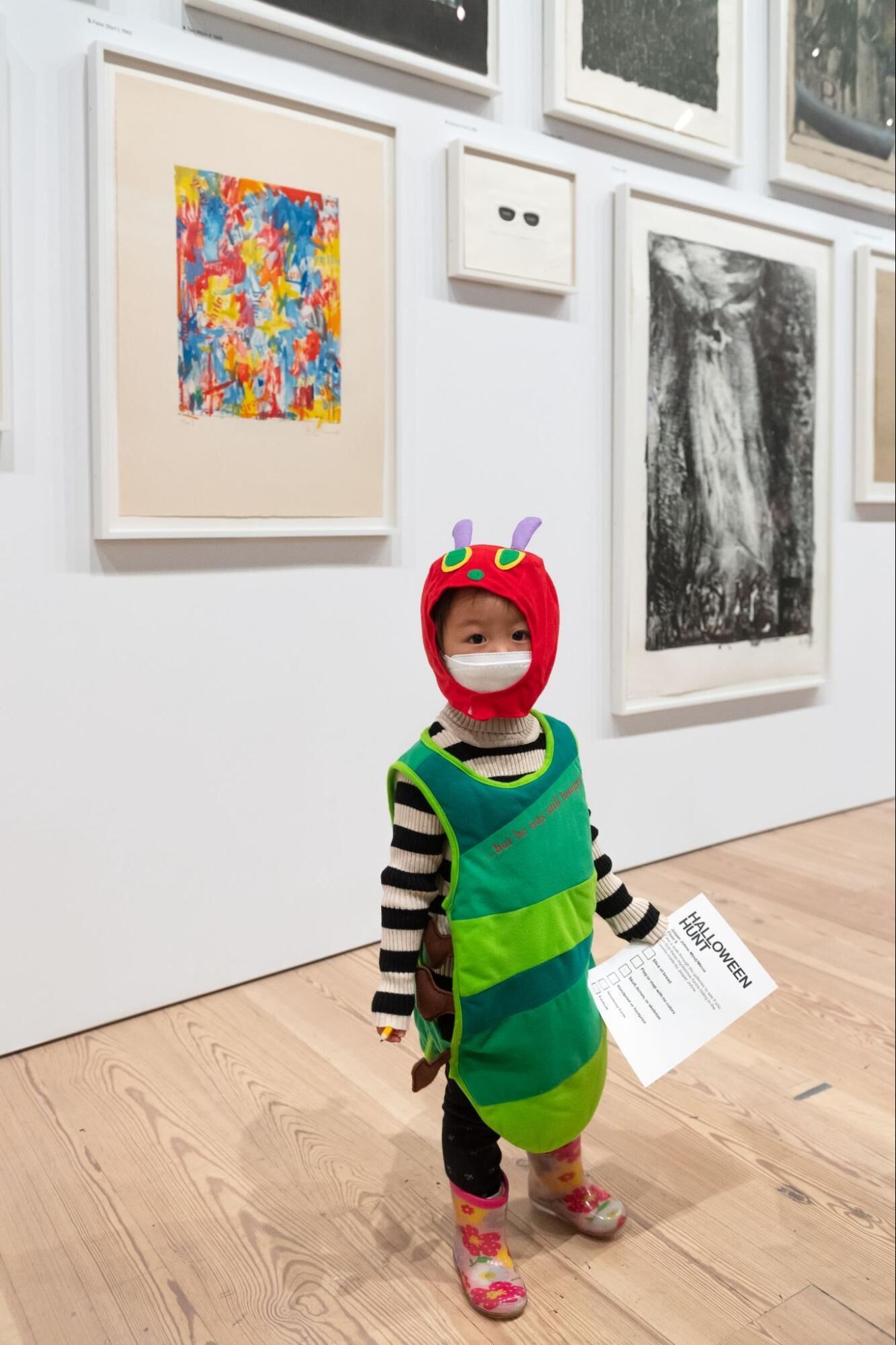 A child wearing a green caterpillar costume poses in the galleries.