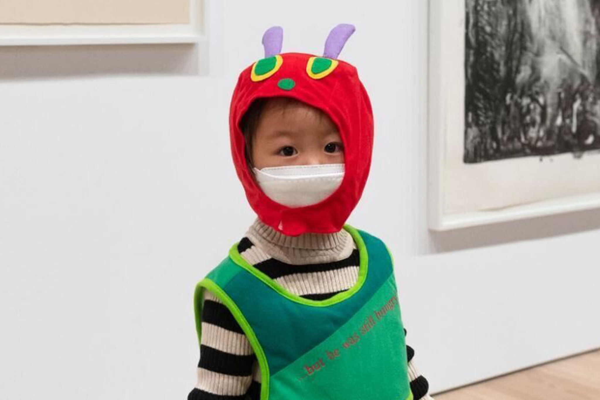 A child wearing a green caterpillar costume poses in the galleries.