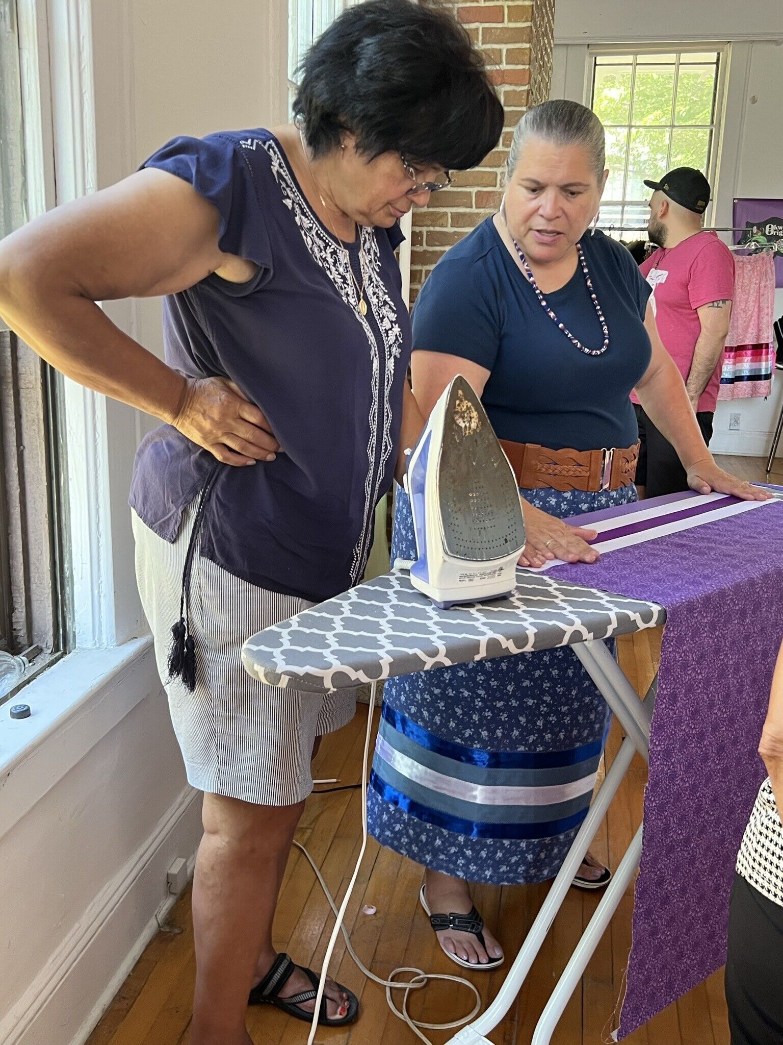 Two people stand over an ironing board.