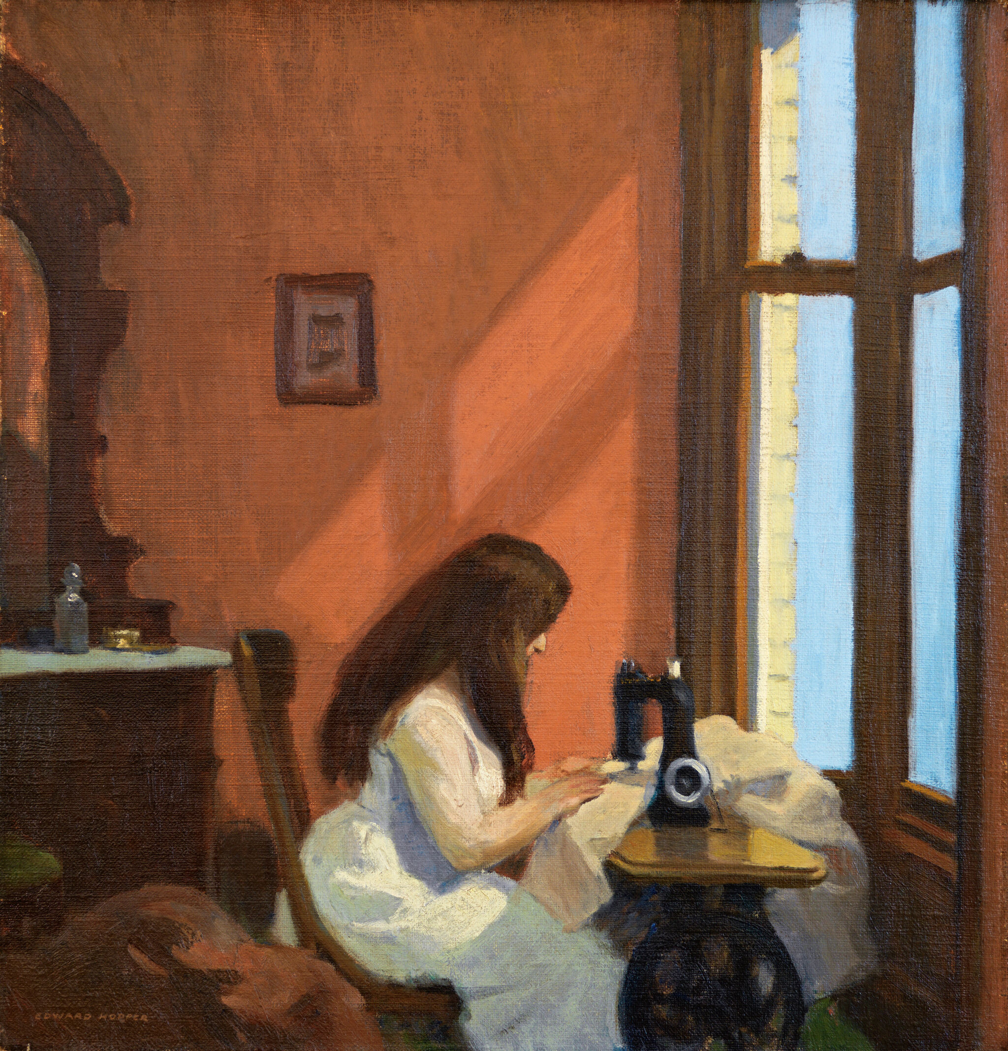 A girl sits at a sewing machine hard at work facing a window.