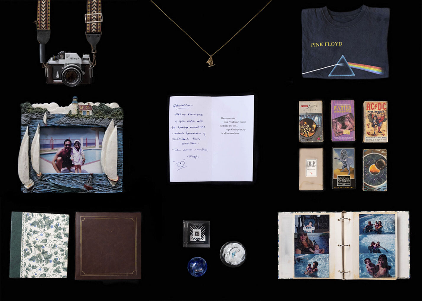 A single-lens reflex camera, a necklace, a T-shirt, a photo frame, cardstock paper, cassette tapes, photo albums and paper weights against a black background.