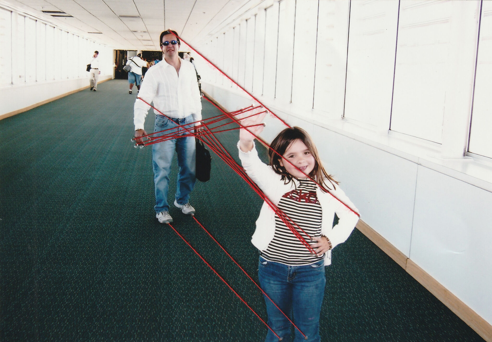A photograph of a man and young girl with lines of red thread attached to the photograph.