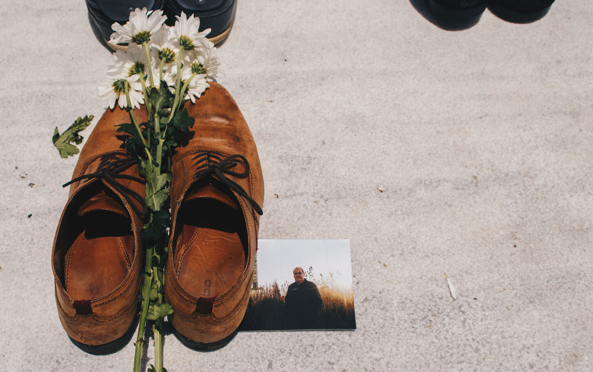 A pair of shoes, flowers, and a photograph of a man.