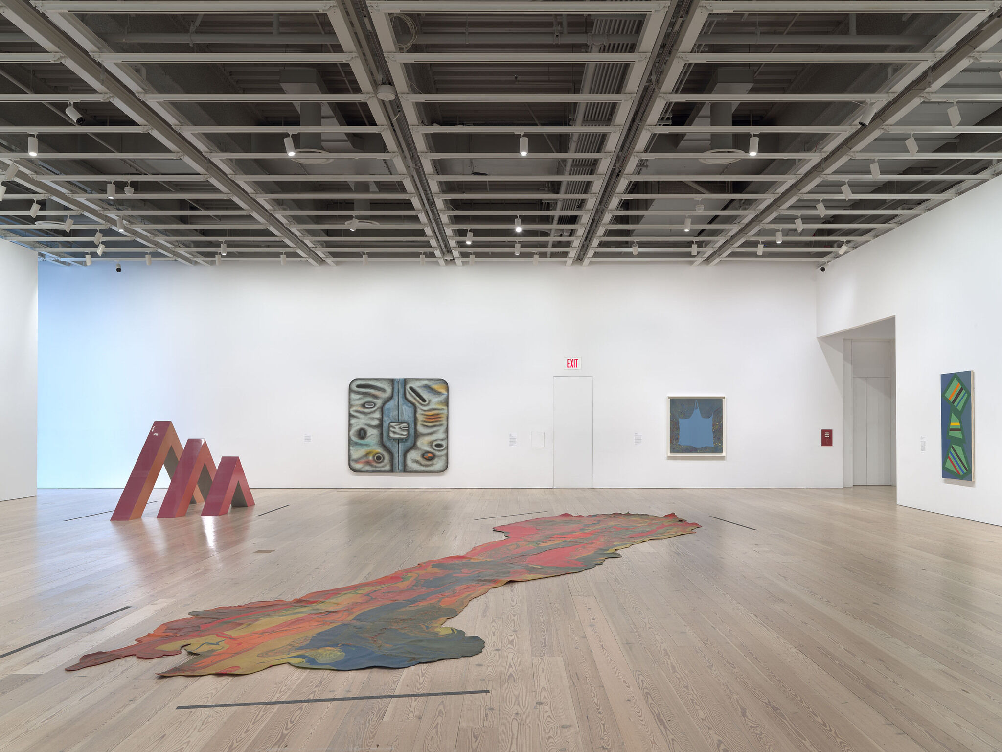 Gallery walls with artwork hung up and sculptures in the center of the space. 
