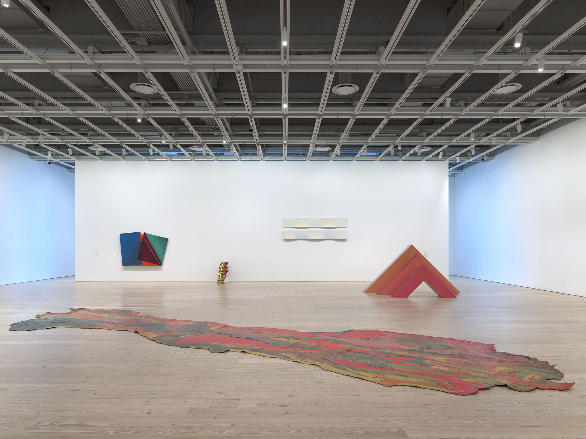 Gallery walls with artwork hung up and sculptures in the center of the space. 