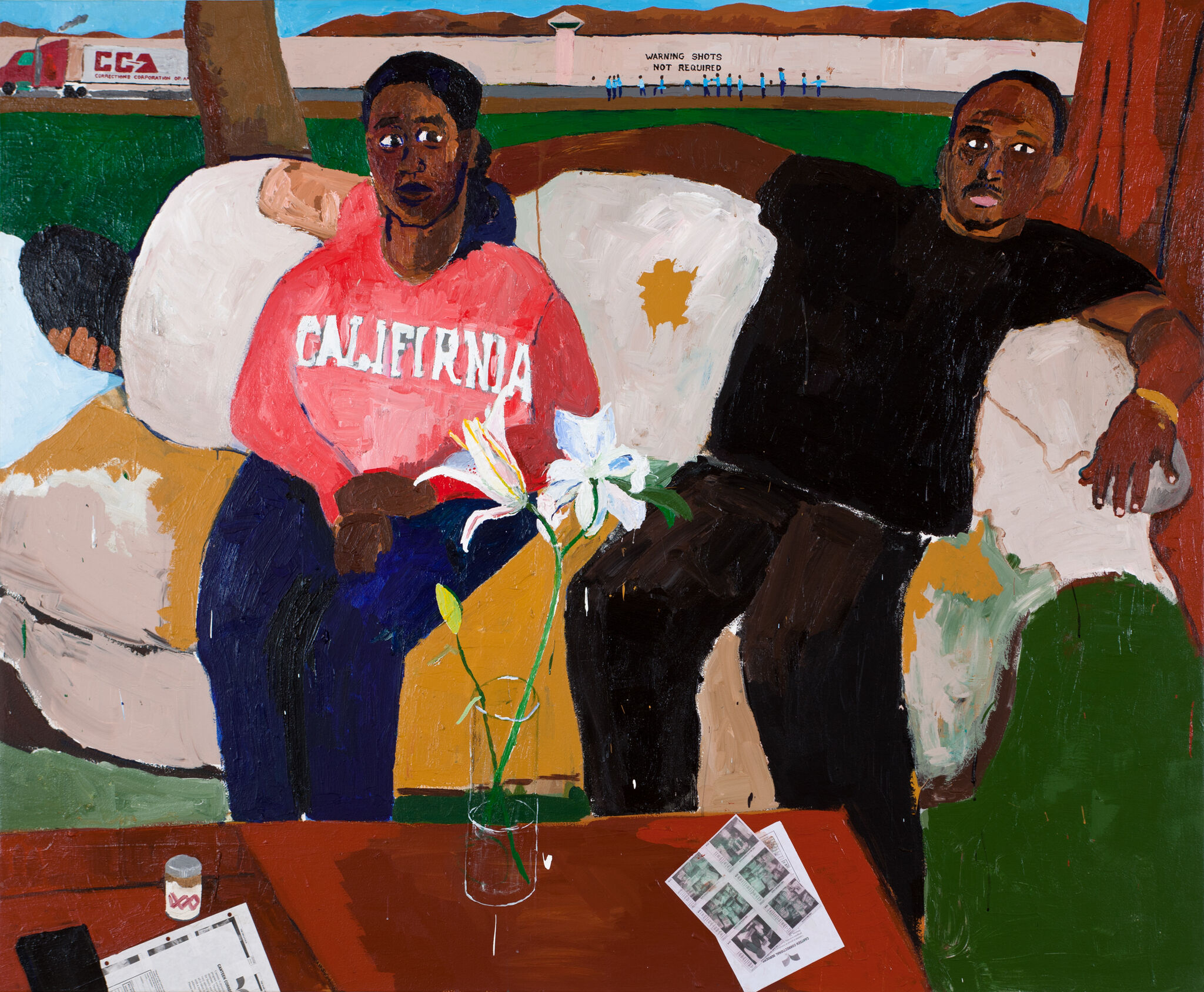 A Black woman and man sit on a couch, in front of a low cofee table. They are seated in a grassy area, with a couple of trees behind them. In the far background is a road with a white wall behind it. The words "warning shots not required" are written on the wall in black letters, and there is a small crowd of Black men in blue uniforms around this area of the wall. 