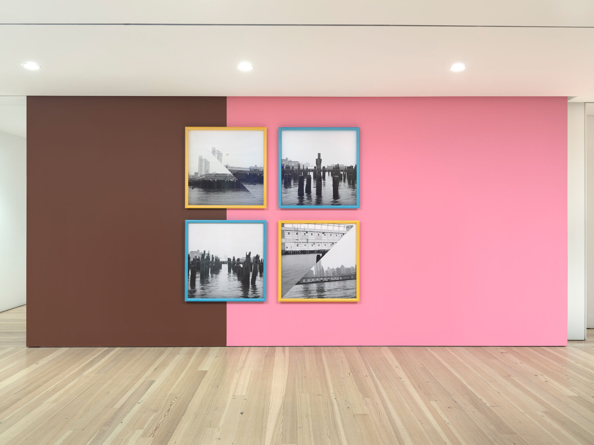 Four black and white photographs of Manhattan's westside waterfront on a pink and black gallery wall.